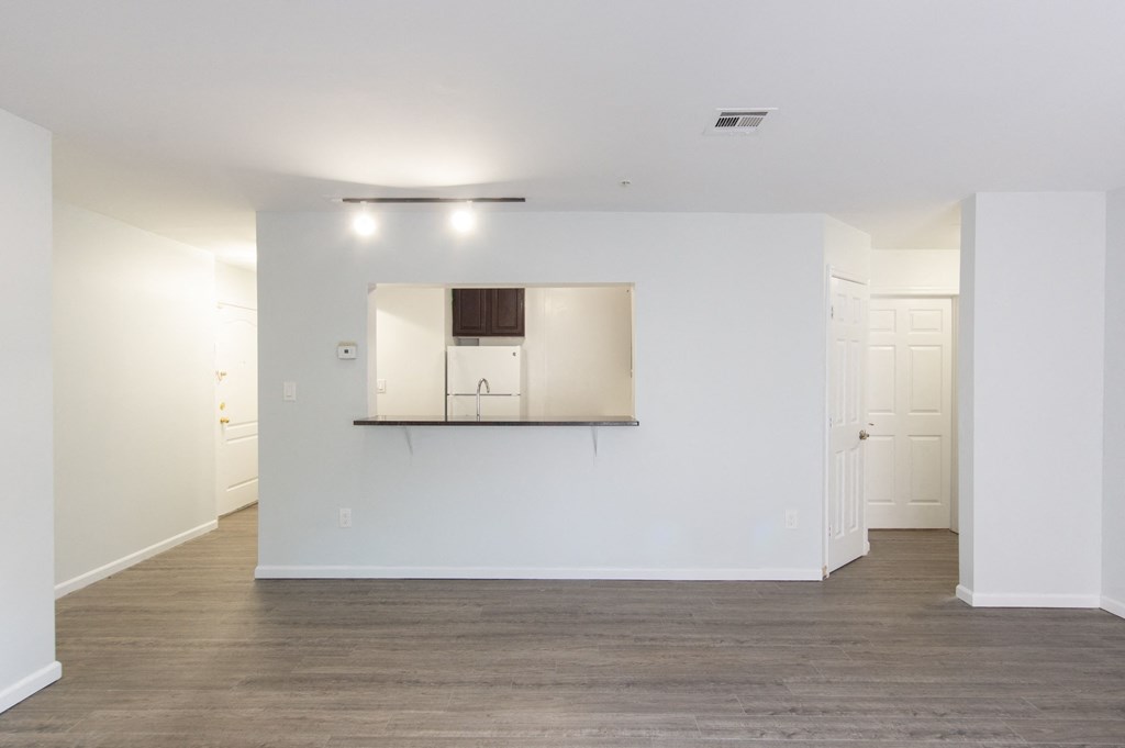 an empty living room with white walls and a kitchen
