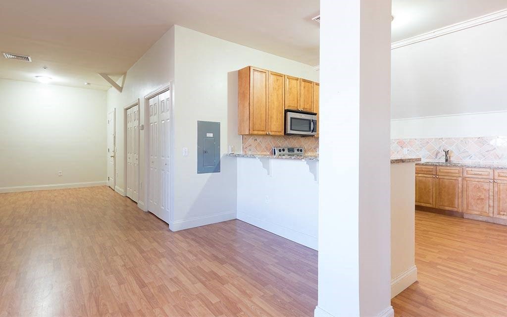 an empty kitchen with a microwave and a wood floor