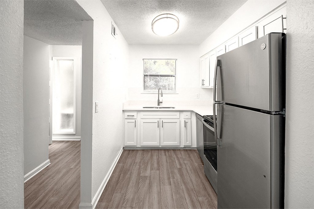 an empty kitchen with stainless steel appliances and white cabinets