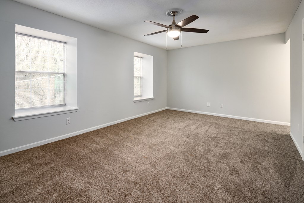 an empty living room with carpet and a ceiling fan