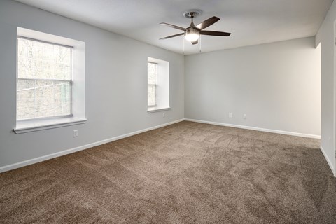 an empty living room with carpet and a ceiling fan