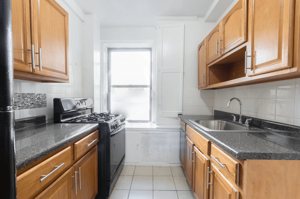 an empty kitchen with wooden cabinets and a window