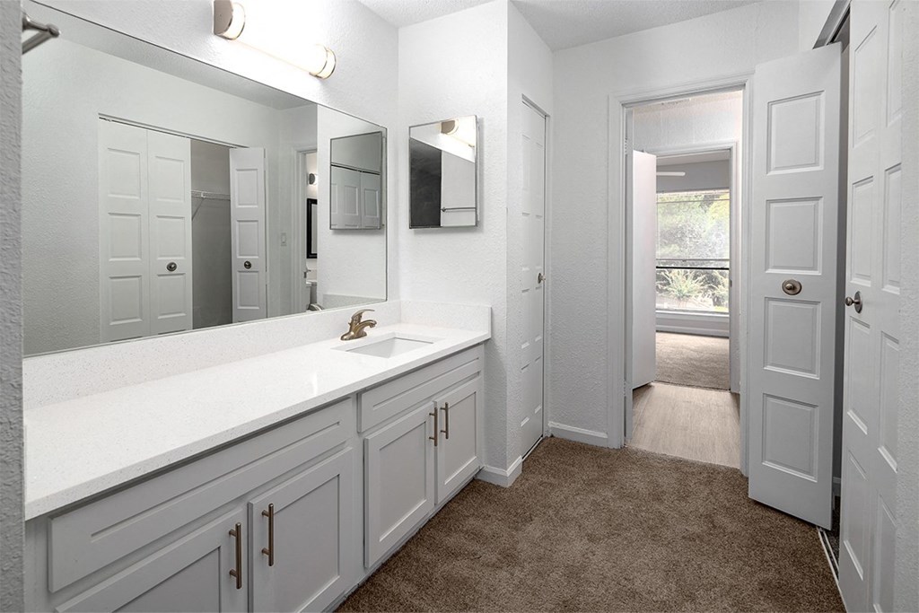 a bathroom with white cabinets and a sink and a mirror