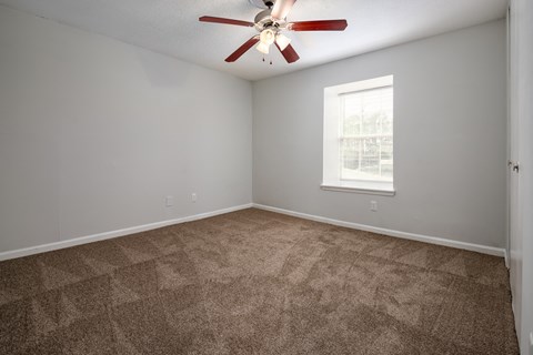 an empty room with carpet and a ceiling fan