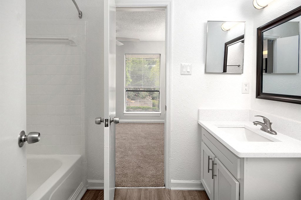 an empty bathroom with a sink and a shower and a window
