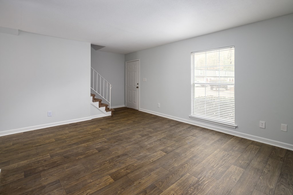 an empty living room with wood flooring and a window