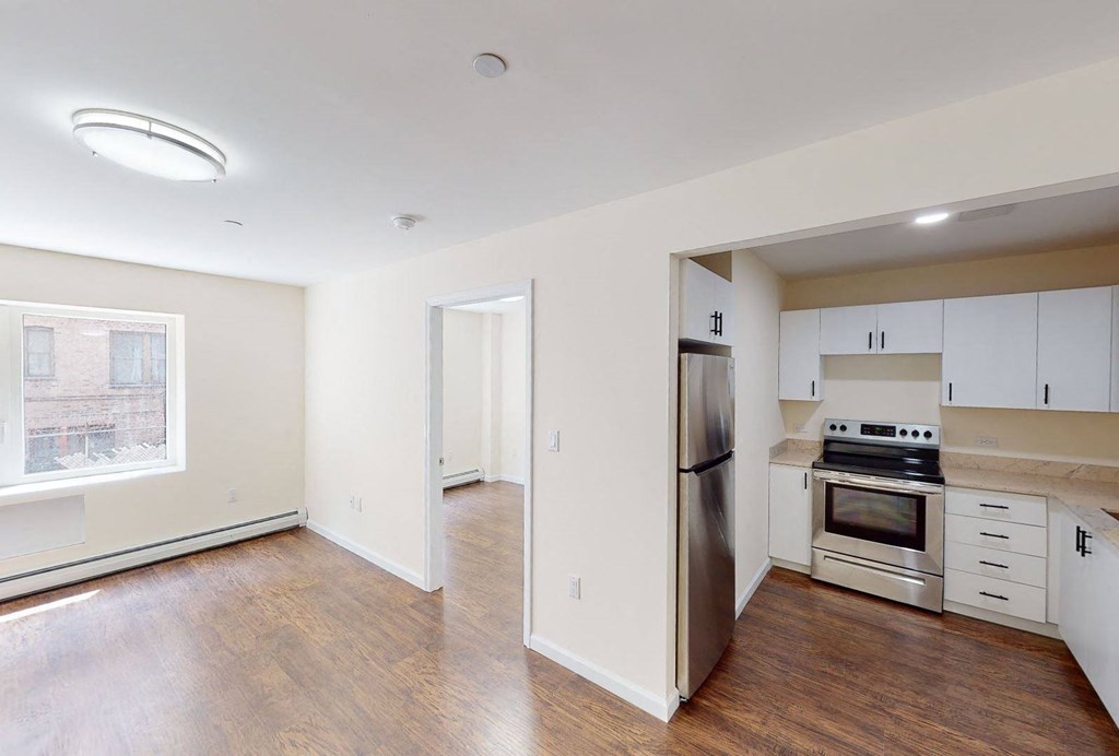 a renovated living room with a kitchen with stainless steel appliances