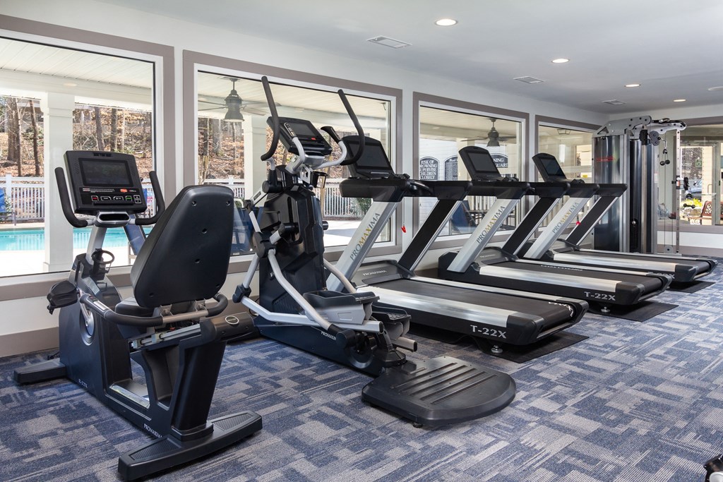 a gym with treadmills and other exercise equipment in a room with windows