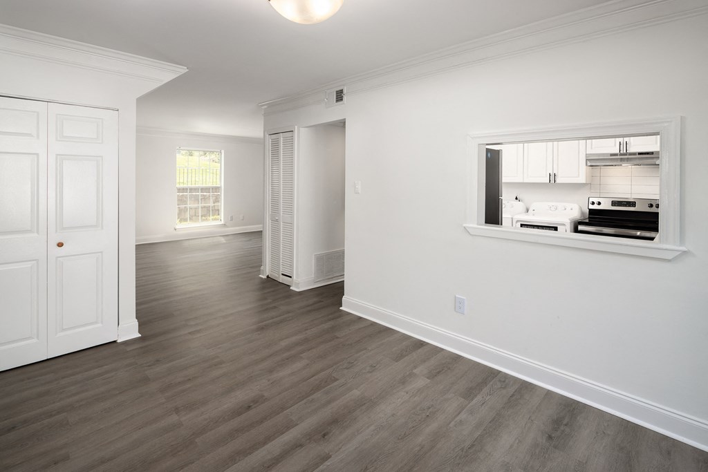a living room and kitchen with white walls and wood floors