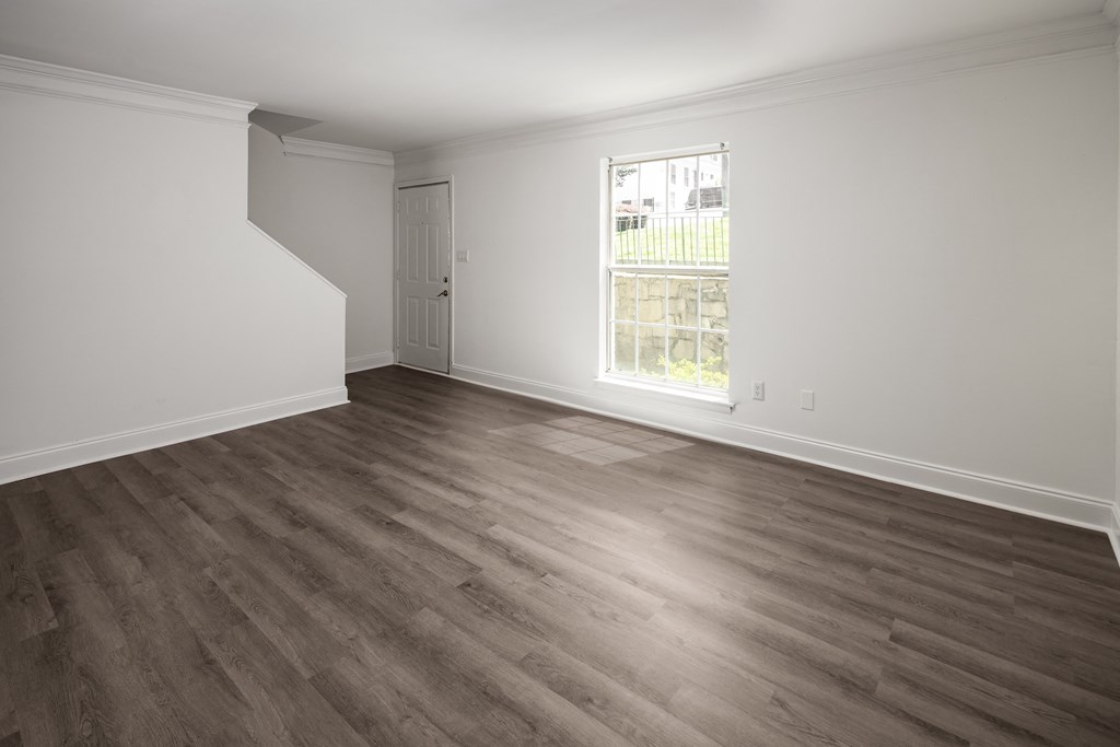 an empty living room with wood floors and a window