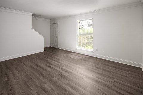 an empty living room with wood floors and a window
