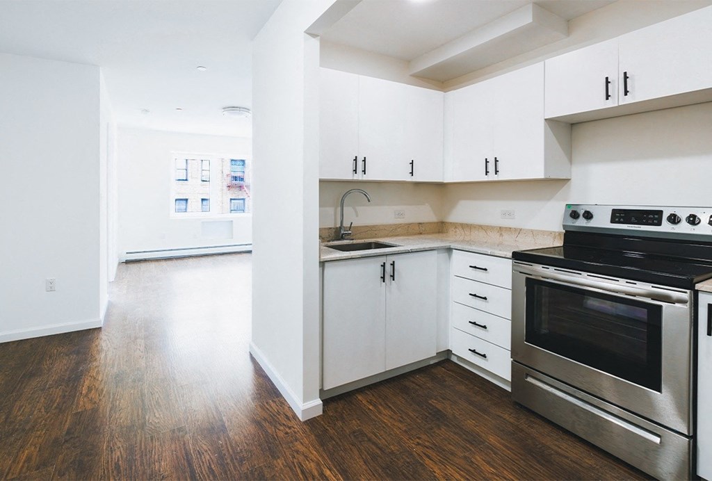 an empty kitchen with stainless steel appliances and white cabinets