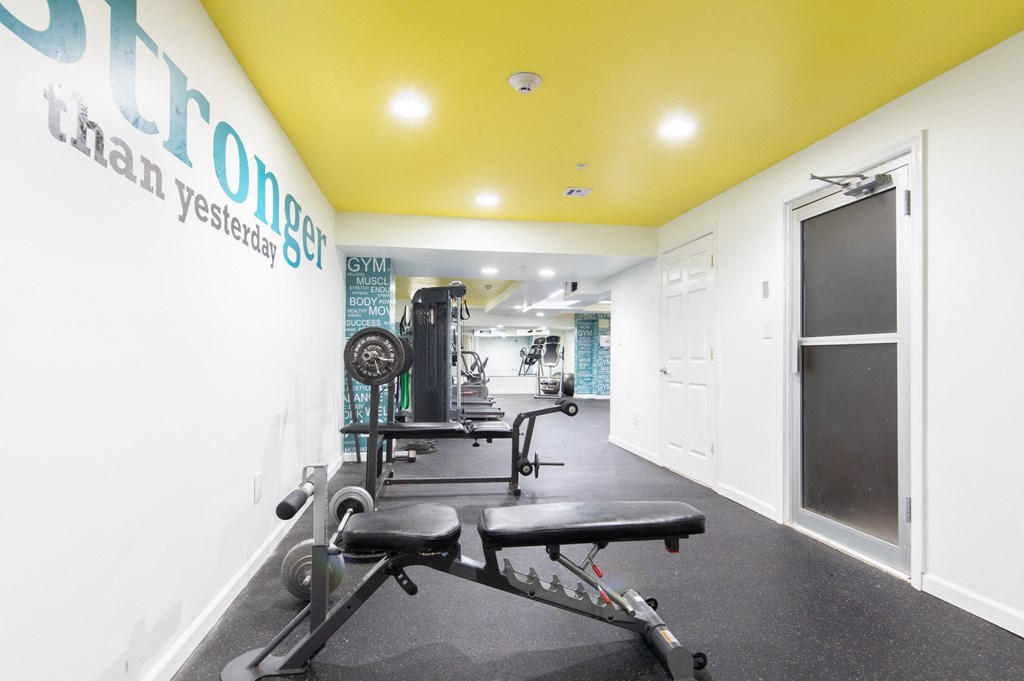 a workout room with weights and a yellow ceiling and white walls