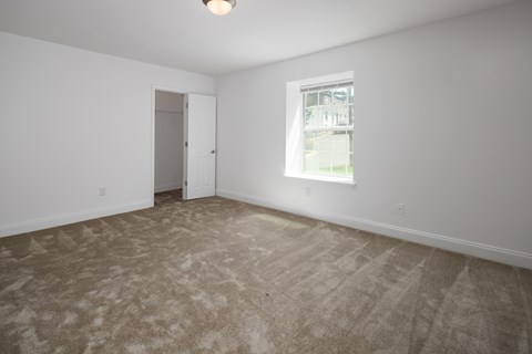 an empty living room with carpet and a window