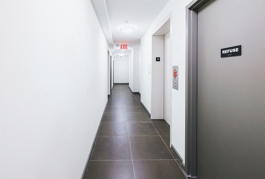 a hallway with white walls and a gray tile floor and doors