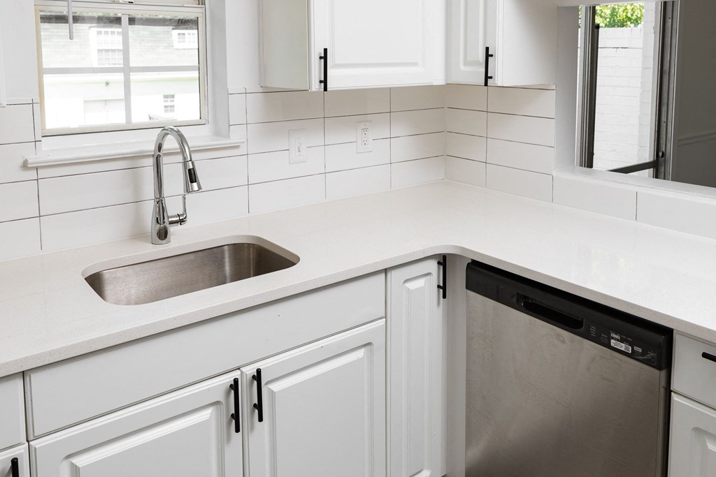 a white kitchen with white cabinets and a stainless steel sink