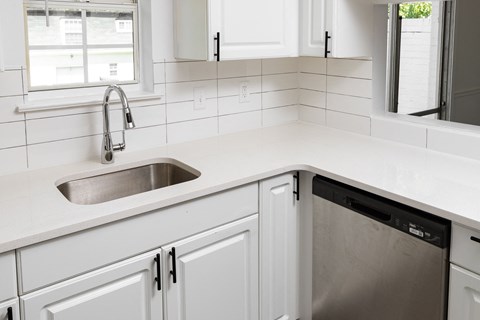 a white kitchen with white cabinets and a stainless steel sink