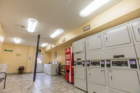 a utility room with a row of washers and dryers and a red machine