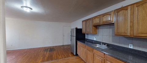 A kitchen with wooden cabinets and a black refrigerator.