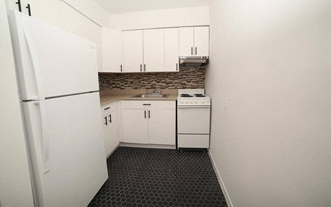 A kitchen with white cabinets and a black and white floor.