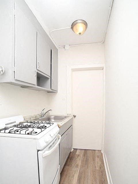 A small white kitchen with a stove and a door.
