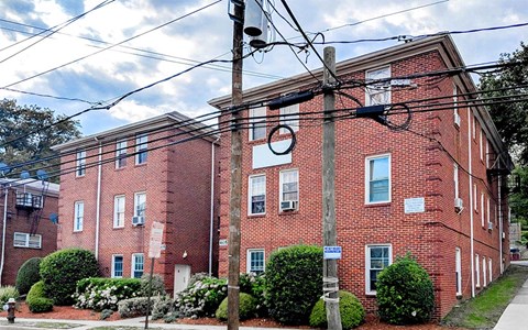 A red brick building with a blue sign on a pole in front.