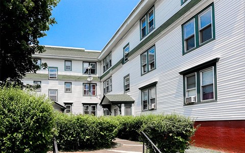 an apartment building with white siding and a red gate