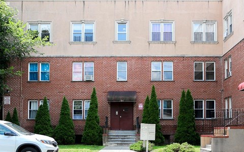 A red brick building with a white car parked in front.