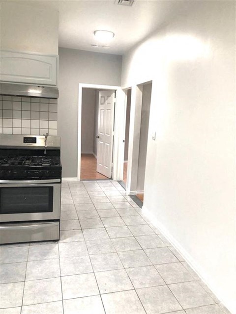 A kitchen with a stove top oven and a tile floor.