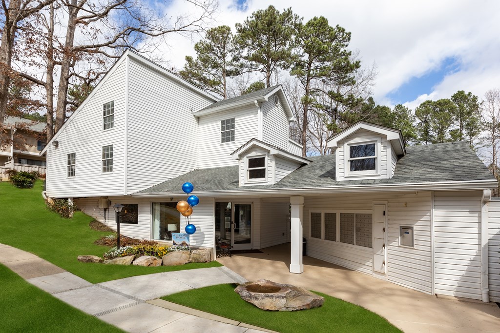 A white house with a grey roof and a balloon arch on the front door.