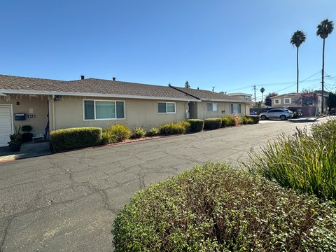 A row of houses with a car parked in the driveway.