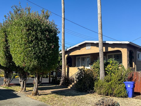 A house with a blue trash can in front of it.