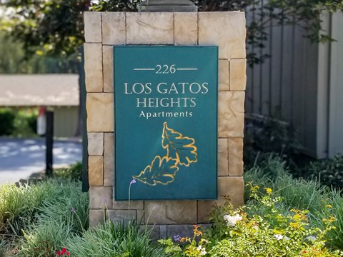 A sign for Los Gatos Heights Apartments is displayed in front of a building.