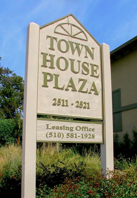 A sign for the Town House Plaza with a phone number for the leasing office.