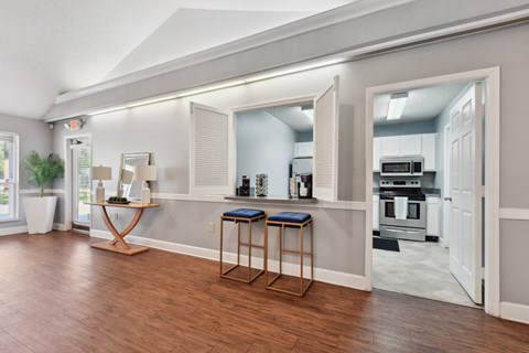 A kitchen with a bar stool and a table in front of a window.