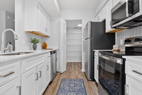 A kitchen with white cabinets and a black refrigerator.