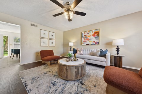 A living room with a white couch, a wooden coffee table, and a ceiling fan.