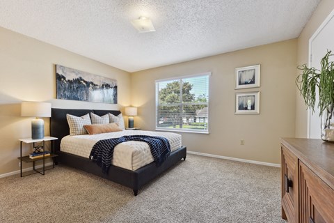 A bedroom with a large bed and a painting on the wall.