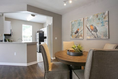 A dining room with a table and chairs and two pictures of birds on the wall.