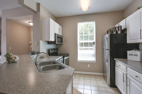 A kitchen with a granite counter top and white cabinets.