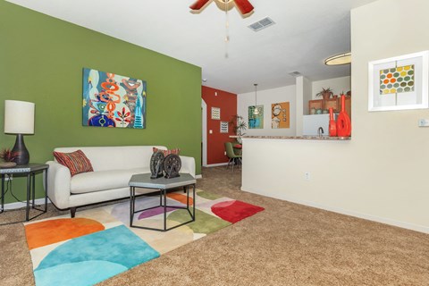 A living room with a white couch and a colorful rug.
