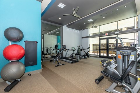 A gym with a variety of equipment including a treadmill, exercise balls, and weights.