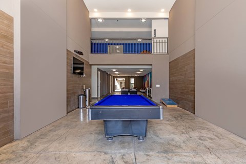 A pool table is in the middle of a room with a balcony in the background.