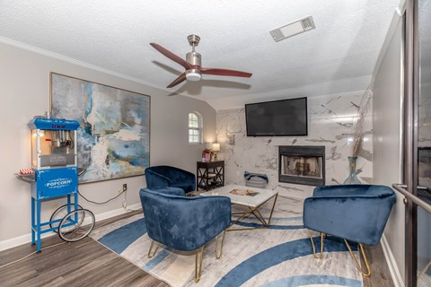A living room with a blue chair and a fan.