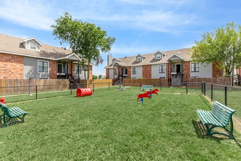 A grassy area with benches and a red object in the middle.