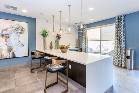A modern kitchen with a white countertop and gold bar stools.
