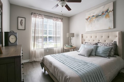 A bedroom with a large bed and a ceiling fan.