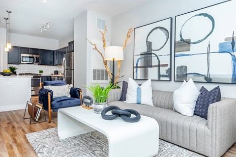 A modern living room with a grey couch, a white coffee table, and a large abstract painting on the wall.