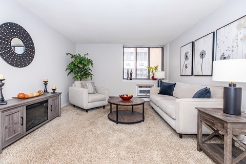 A living room with a white couch, a wooden coffee table, and a large mirror on the wall.