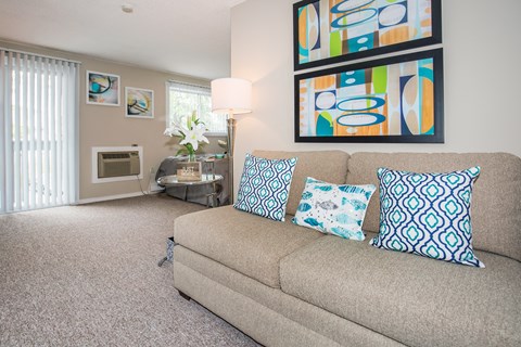 A living room with a couch, pillows, and a painting on the wall.